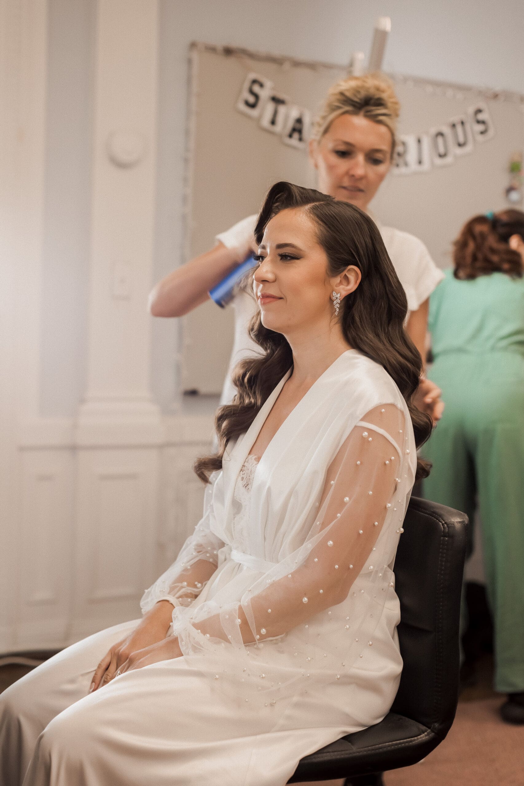Hairstylist preparing the bride for her hairdo.