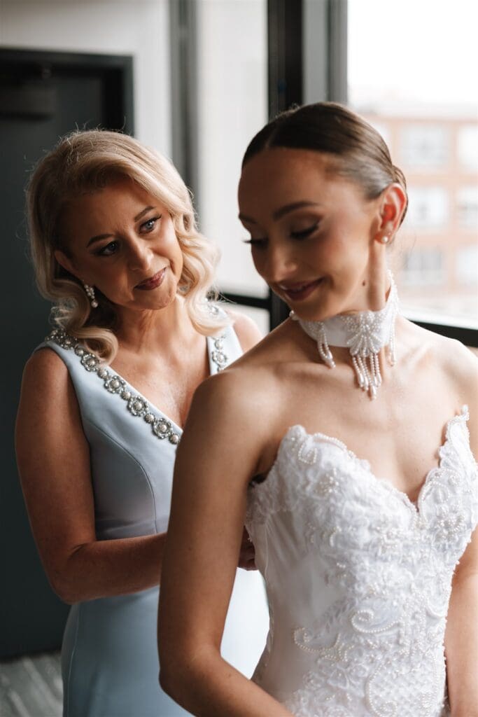 Bride getting ready wearing bridal gown with her mom