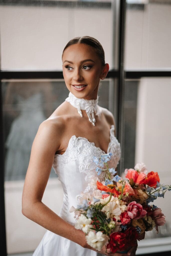 Bride getting ready wearing her bridal gown holding a bouquet