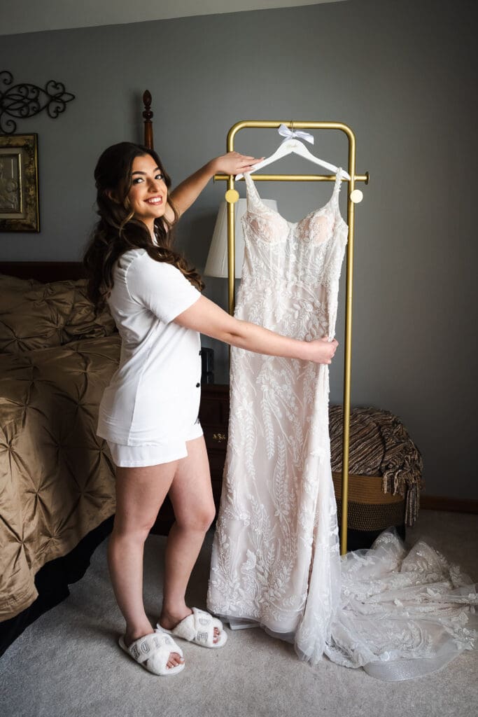 Bride getting ready and holding her wedding dress.