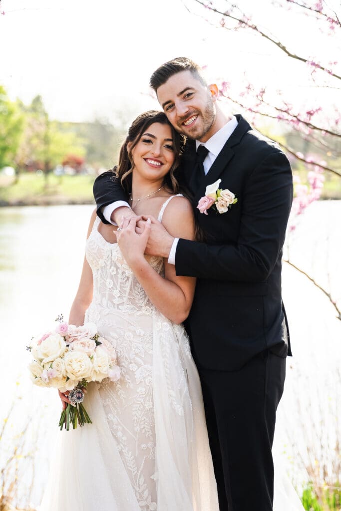 Bride and groom posing for a photograph on a lake.