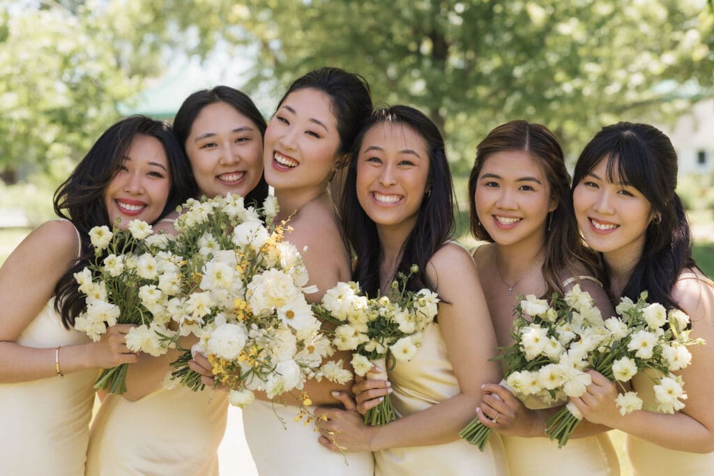 Asian bride and her bridesmaids looking happy and smiling for the camera.