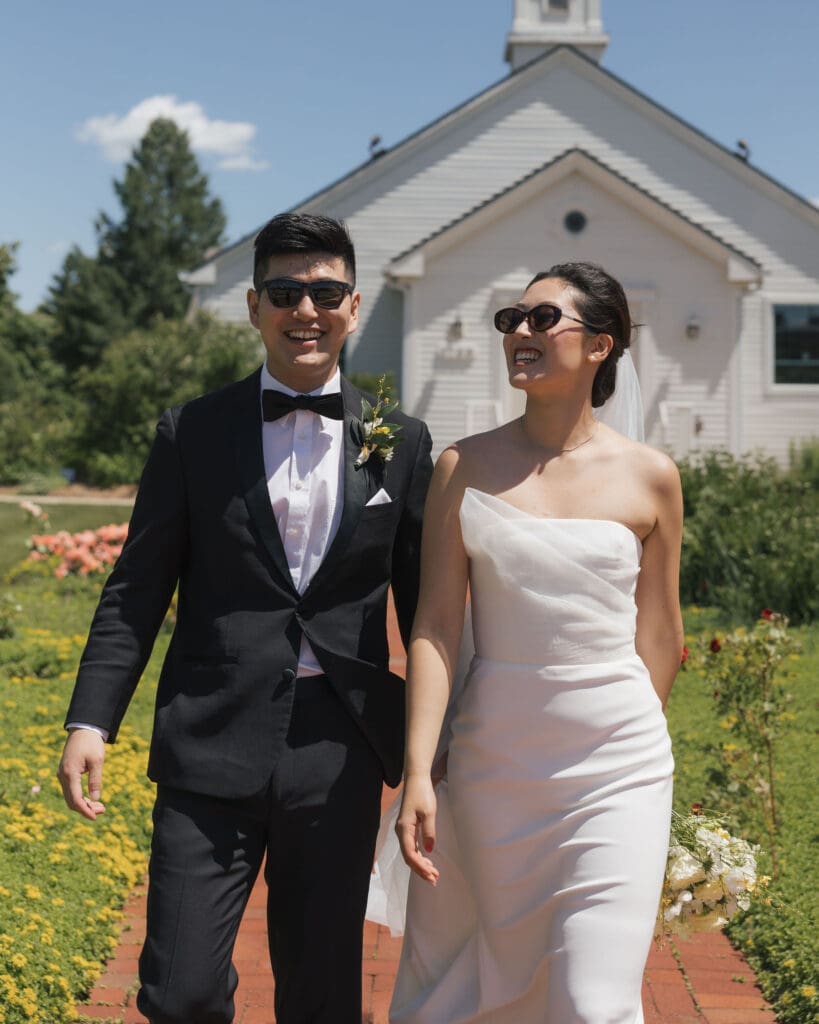 Asian bride and groom walking side by side outside a church.