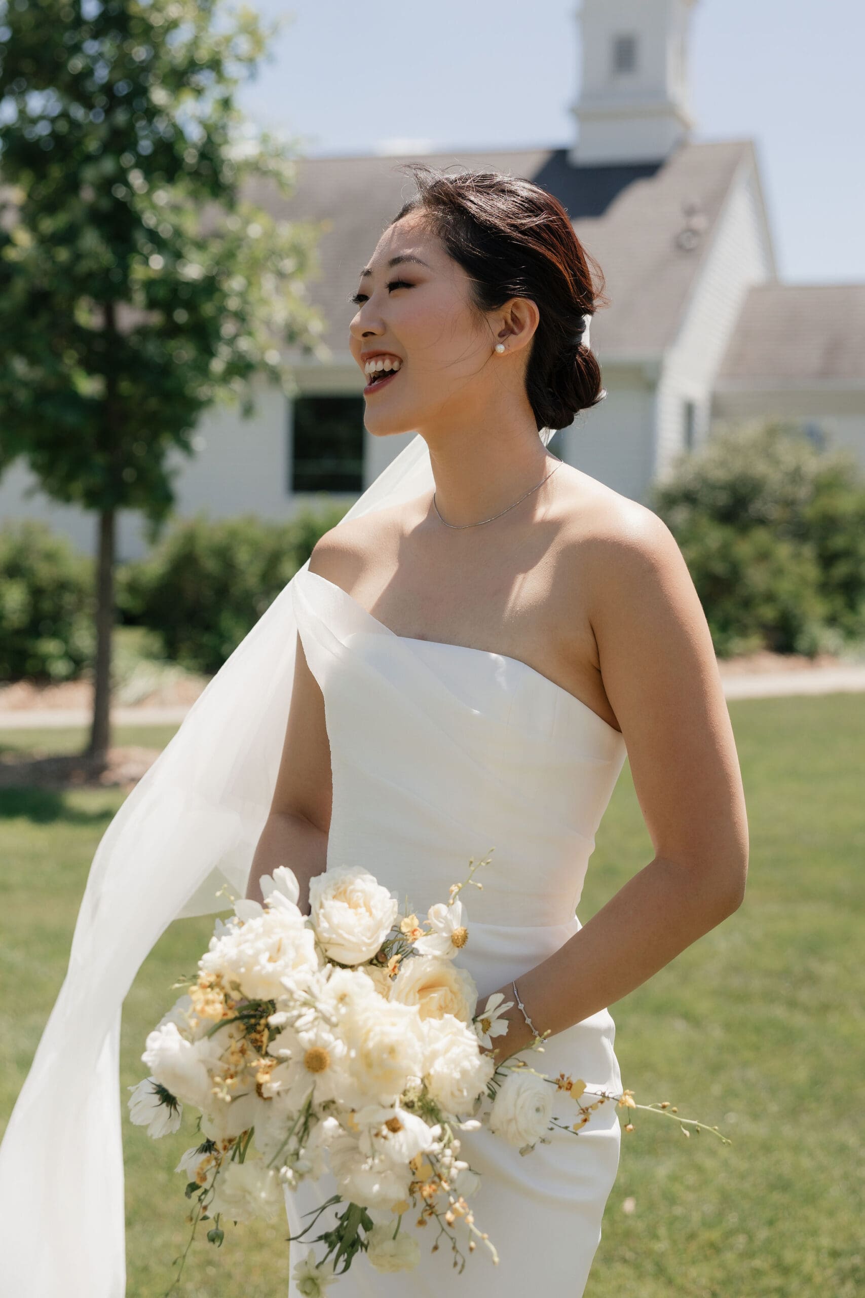 Asian bride posing for the camera and holding a bouquet.