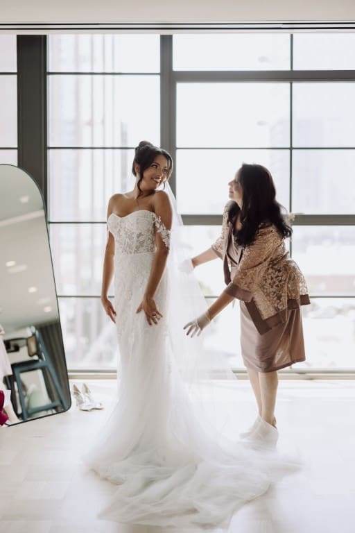 Bride wearing off shoulder wedding gown with her mother.