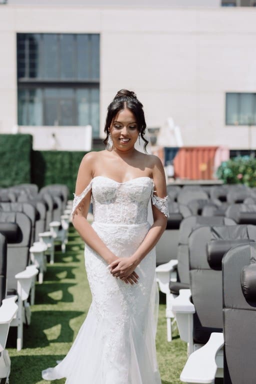 Bride wearing off shoulder wedding gown smiling.