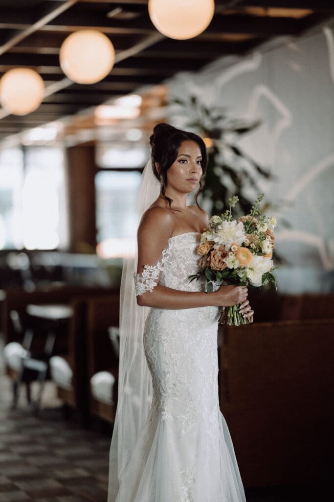 Bride wearing off shoulder wedding gown holding a bouquet.