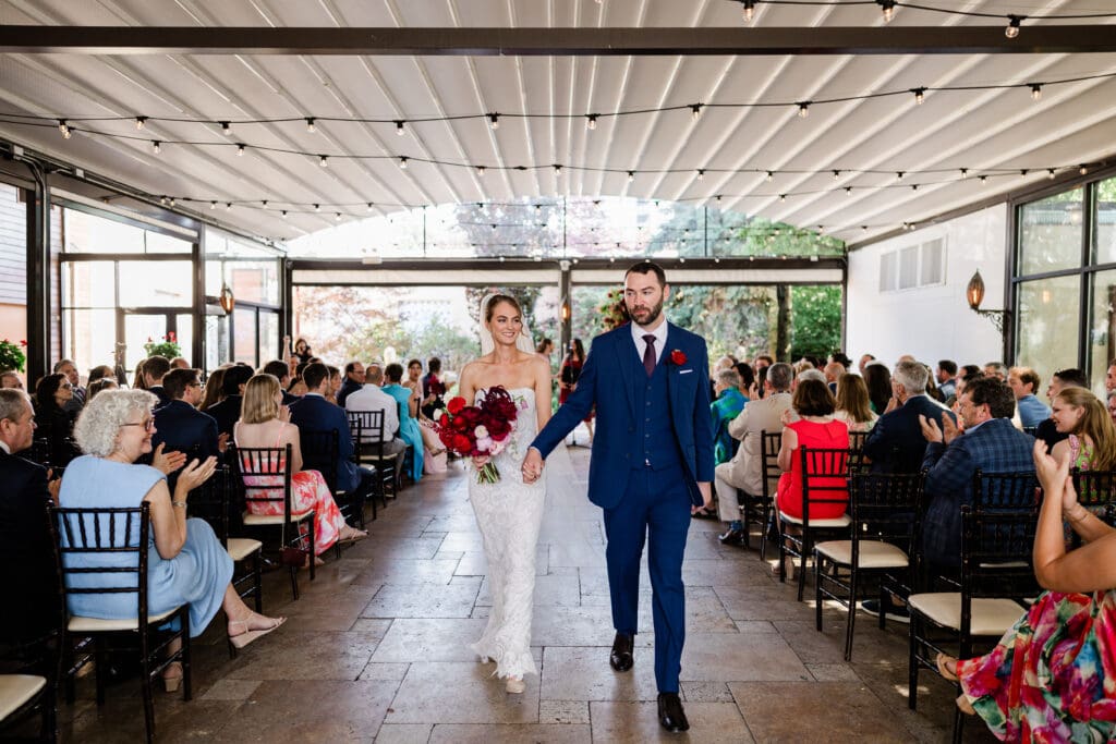 Bride and groom with holding hands walking down the aisle.