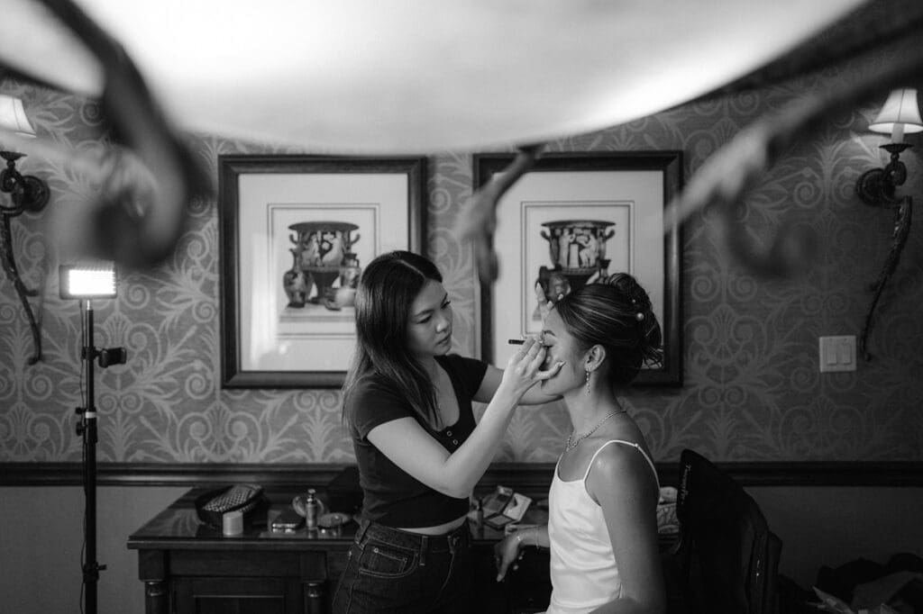 Bride with her makeup artist getting makeup on.
