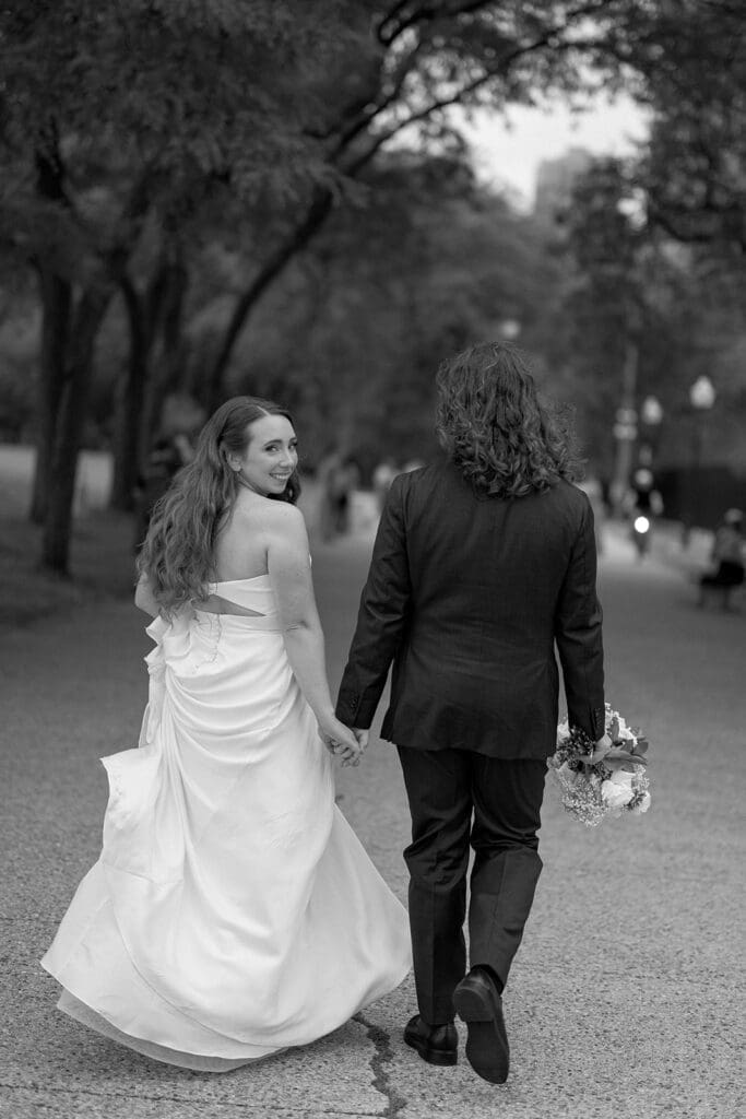 Couple holding hands with their wedding rings visible, sharing a tender moment outdoors.