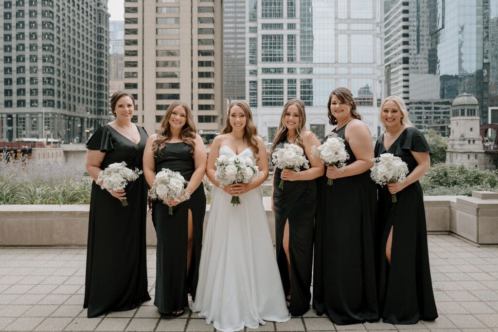 Bride surrounded by her bridesmaids, laughing and posing together outdoors, capturing pre-wedding excitement.