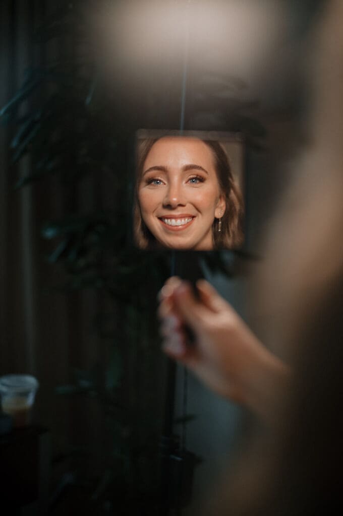 Bride smiling at the mirror.