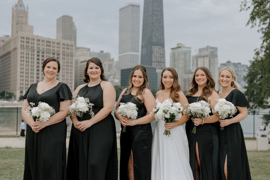 Bride smiling with her bridesmaids, all in coordinated dresses, sharing a joyful moment before the ceremony.