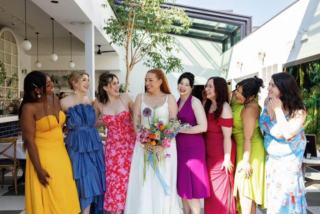 Bride celebrating with her bridesmaids, all smiling and cheerful.