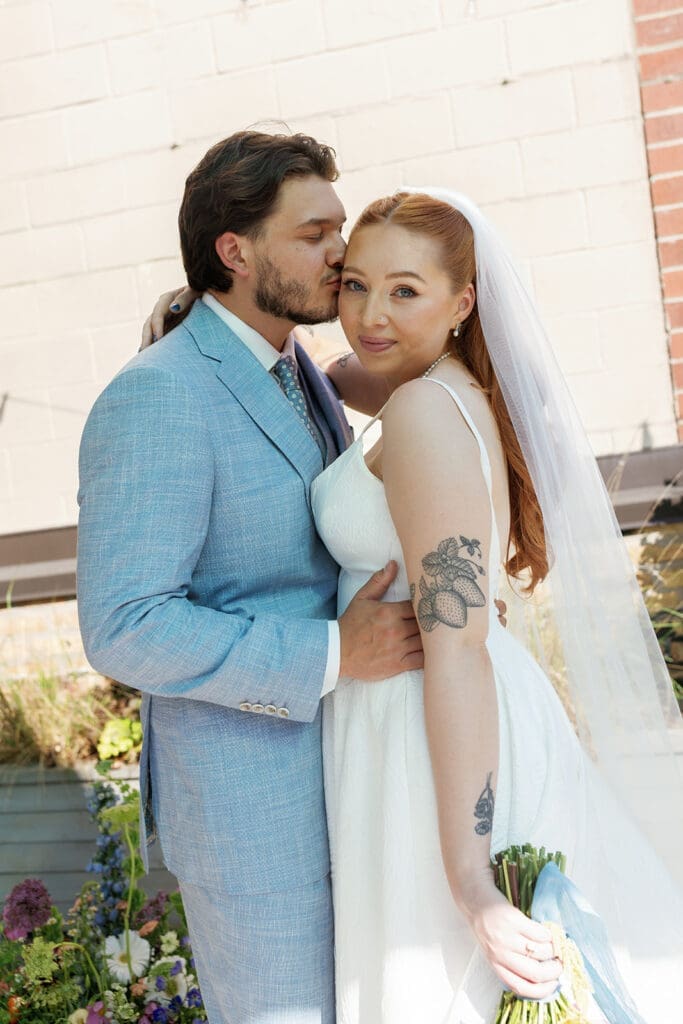 Bride and groom smiling and kissing as newlyweds.