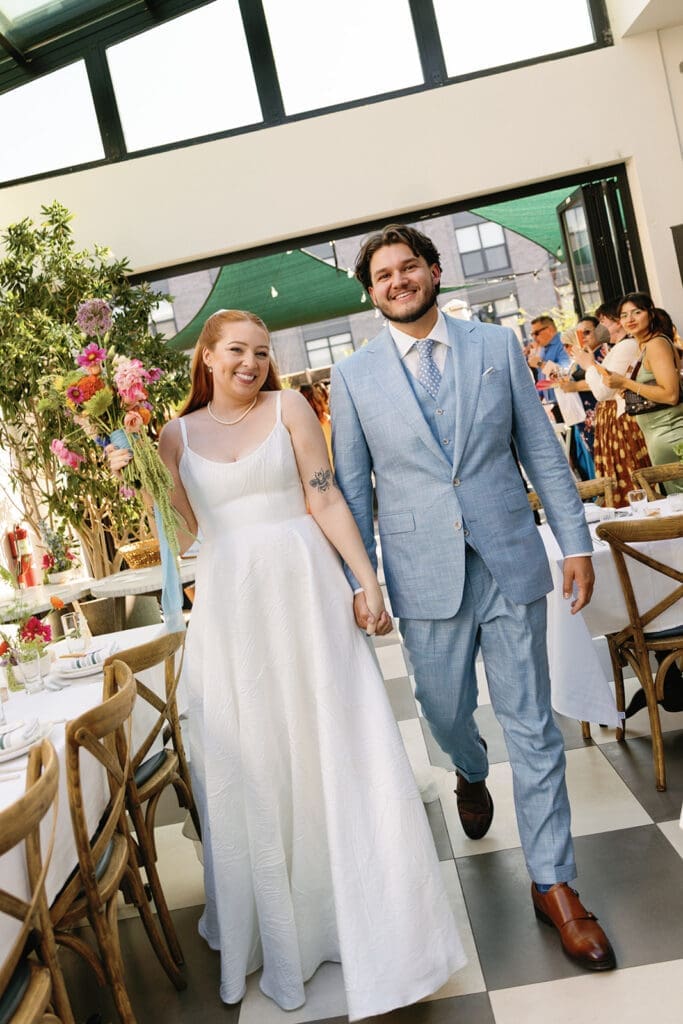 Bride and groom holding hands, smiling while walking down the aisle.