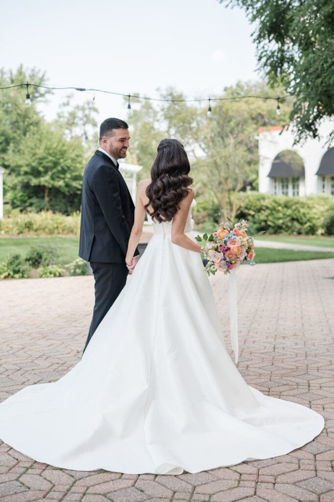 Bride and groom holding hands, walking together, smiling at each other on their wedding day.