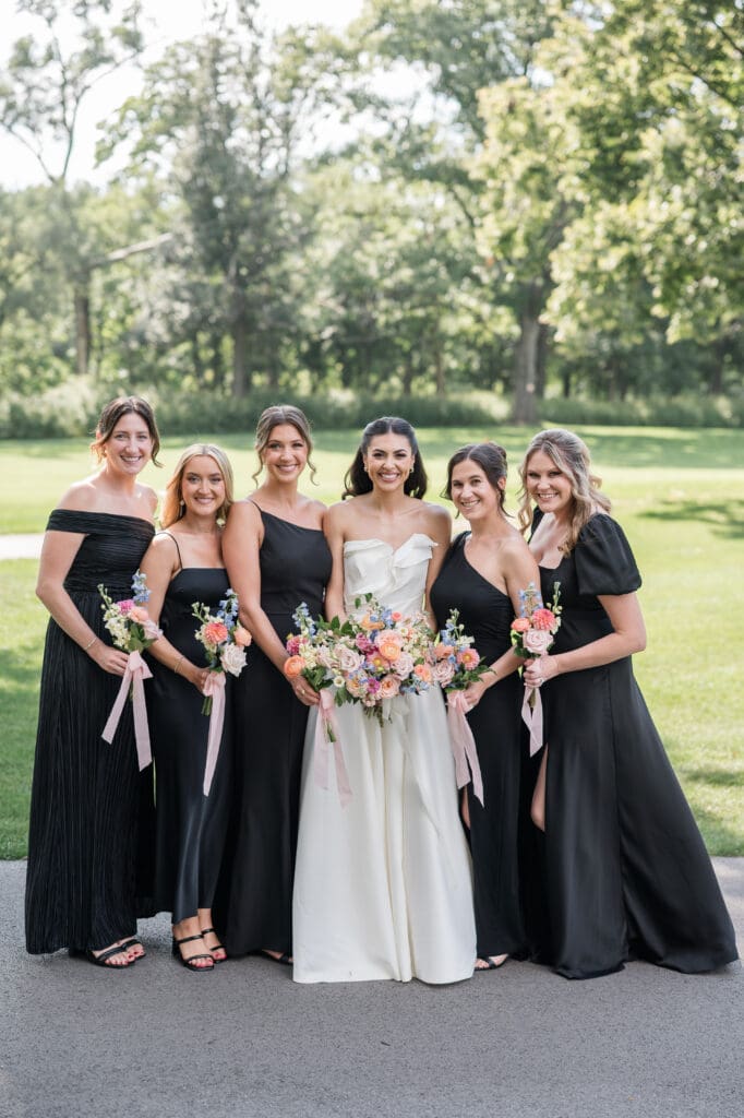 Bride smiling with her bridesmaids, all in coordinated dresses, sharing a joyful moment.