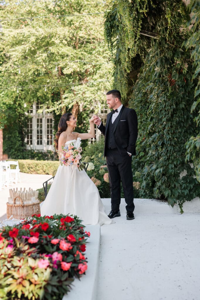 Bride strolling along a garden path, holding her bouquet, with soft sunlight highlighting her dress.