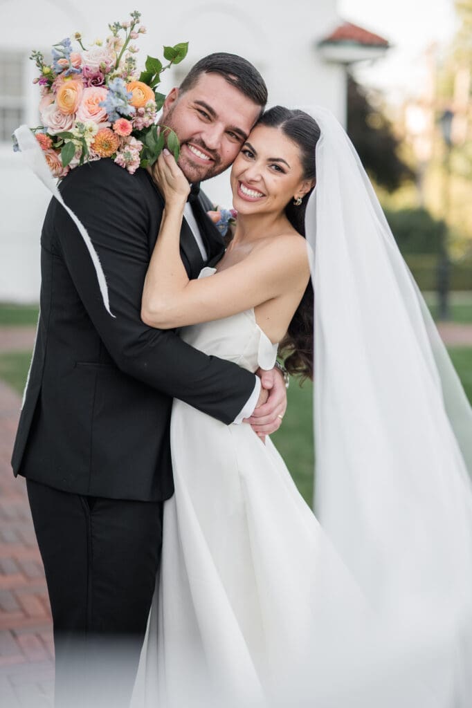 Bride and groom holding hands, smiling at each other on their wedding day.