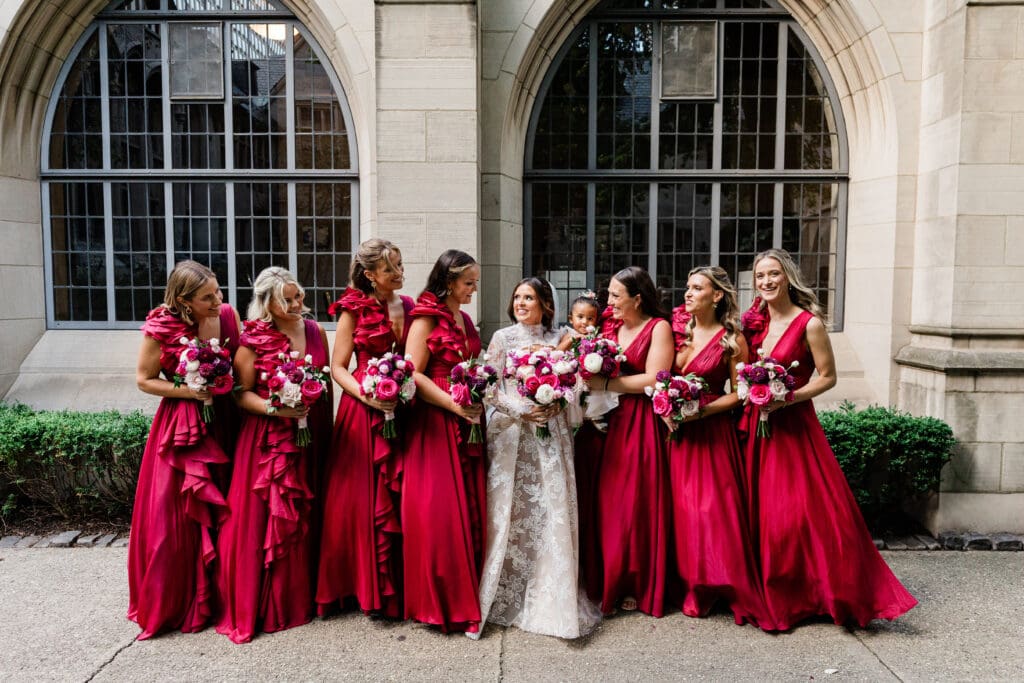 Bride smiling with her bridesmaids, all in coordinated dresses, sharing a joyful moment before the ceremony.