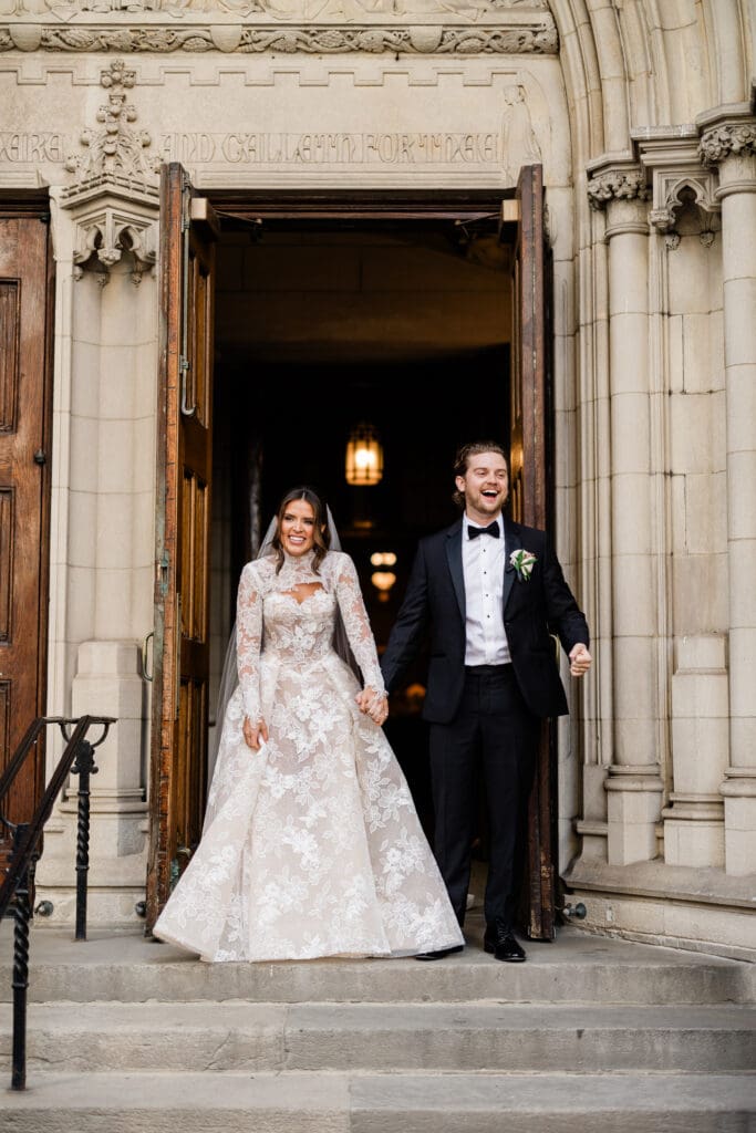Bride and groom holding hands, walking together, smiling at each other on their wedding day.