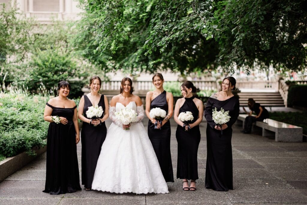 Chicago bride holding a bouquet with her bridesmaids posing in classic bridal gown